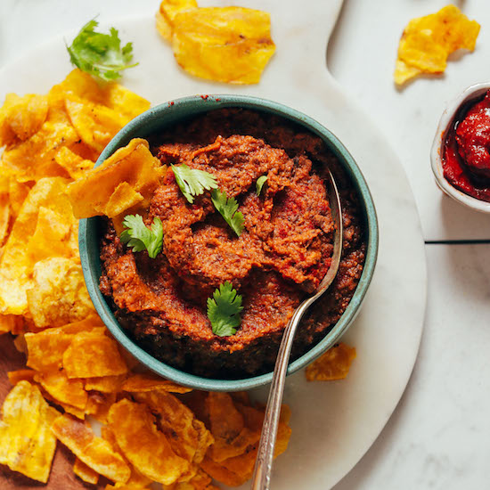 Top down shot of a bowl of Smoky Refried Lentils topped with cilantro and surrounded by plantain chips