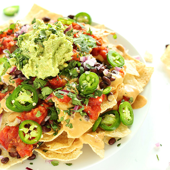 Plate of The Best Damn Vegan Nachos made with cashew queso, salsa, guac and more